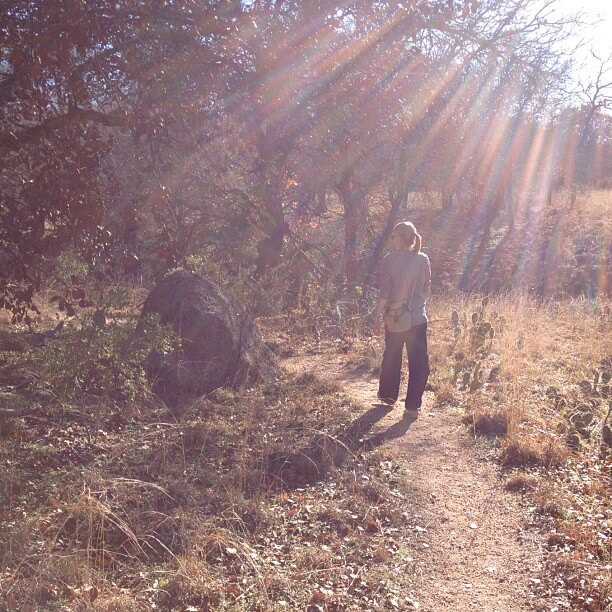 Girl walking along sunny woodland path